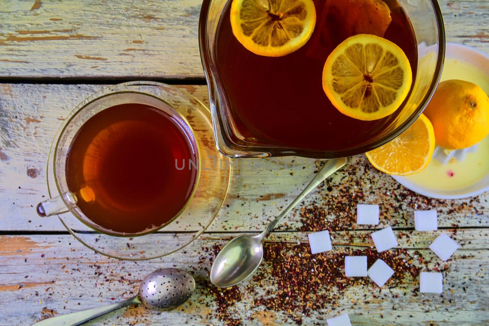 Black tea, a cup of black tea, manual squeezer with lemons. A jug of black tea and cubes of sugar. Top view, flat design by roman_nerud