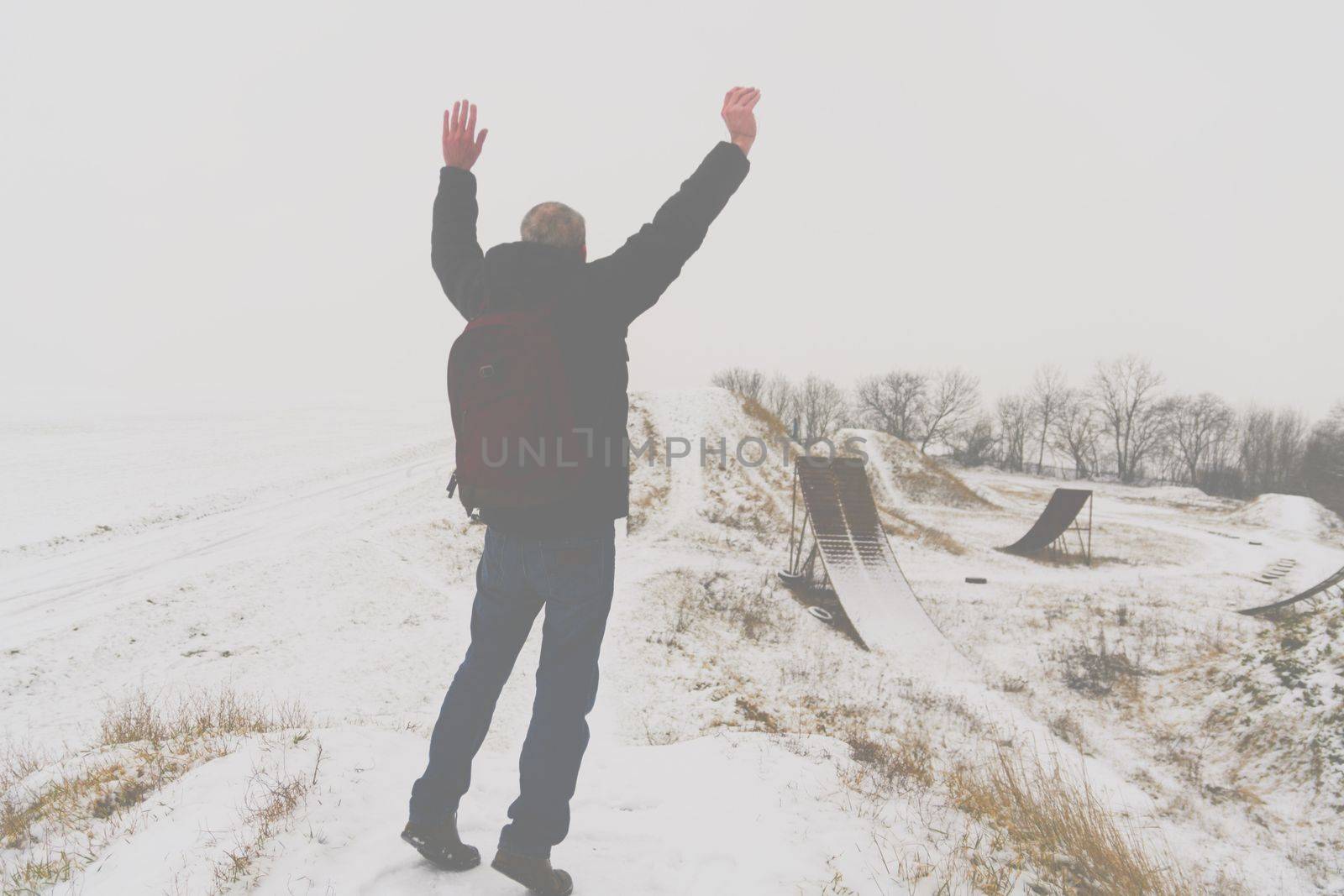 Middle age man jumping happily in beautiful winter landscape . Add haze effect by roman_nerud