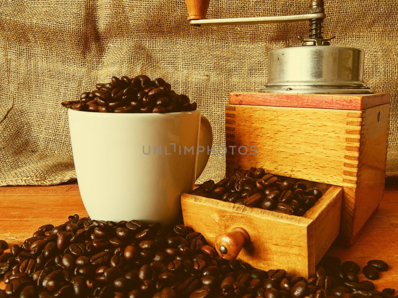 Vintage coffee mill, coffee beans and white cup filled coffee beans on wooden background by roman_nerud