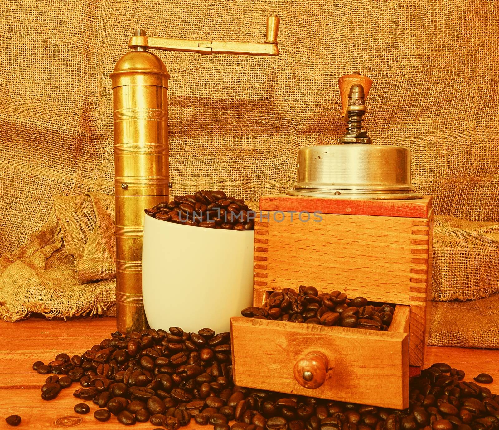 Vintage coffee mills, coffee beans and white cup filled coffee beans on wooden background by roman_nerud