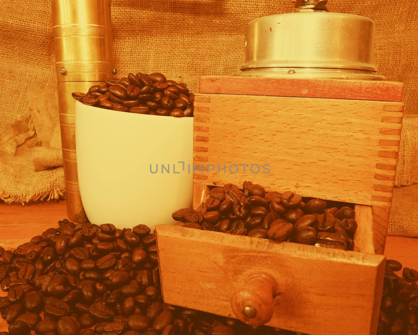 Vintage coffee mills, coffee beans and white cup filled coffee beans on wooden background by roman_nerud