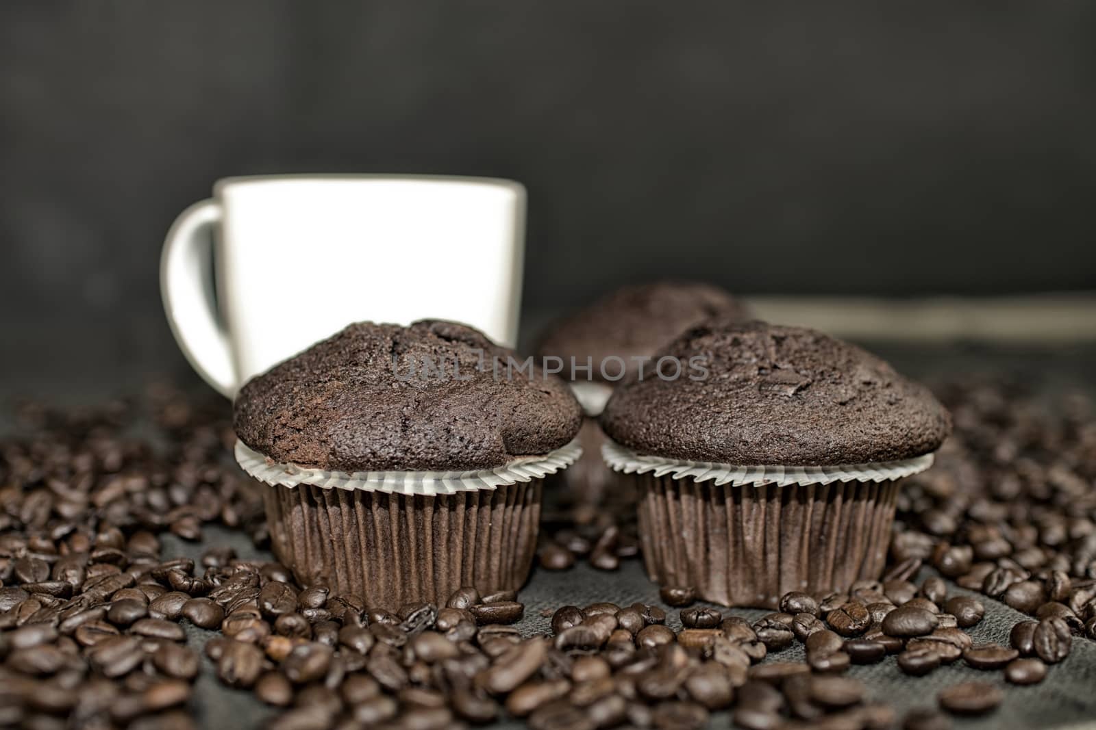 Dark muffin, cups of coffee and coffee beans on black background. Add dark contrasts by roman_nerud