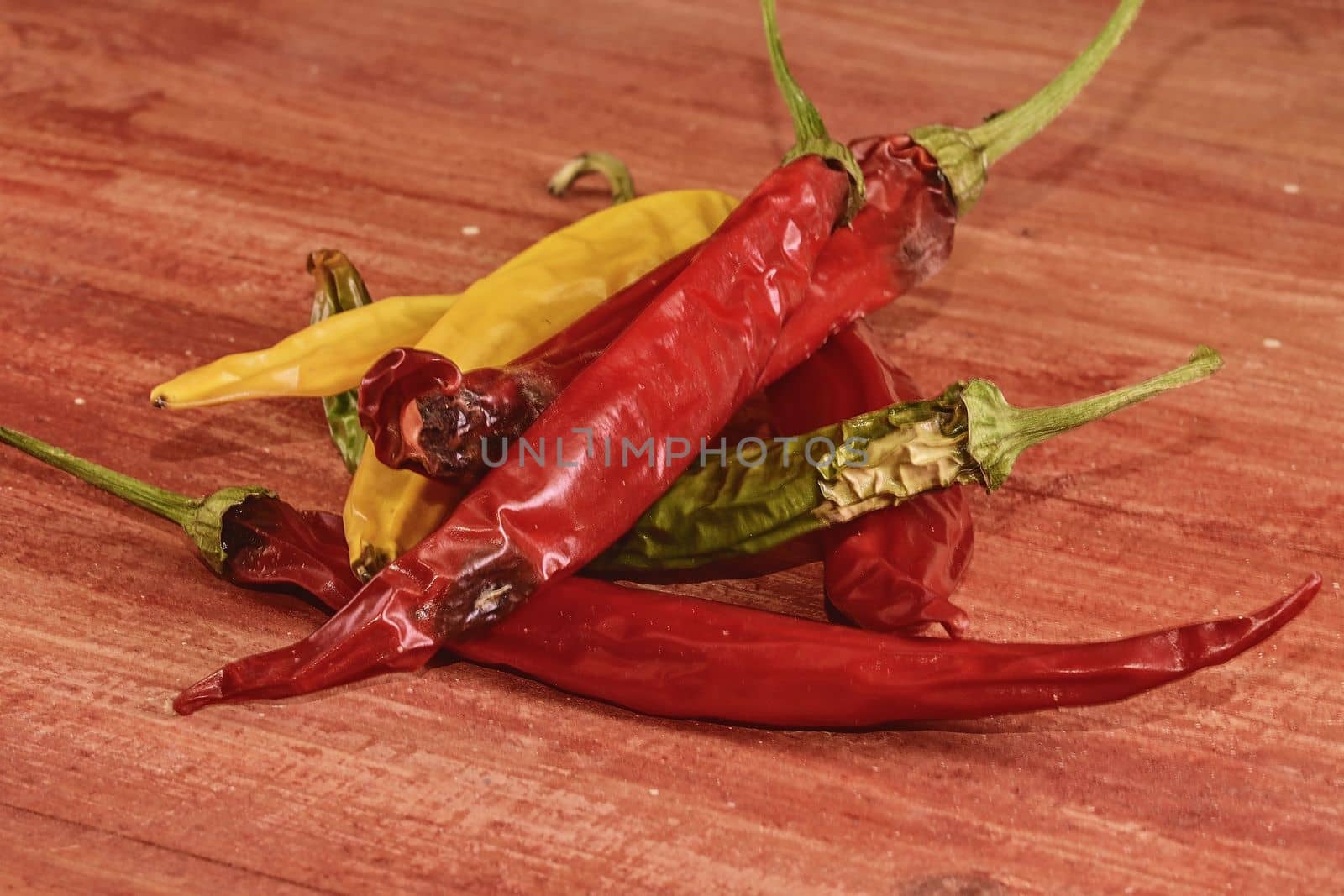 Shrinking and mould chili peppers on red wooden background. Rotten chili peppers.