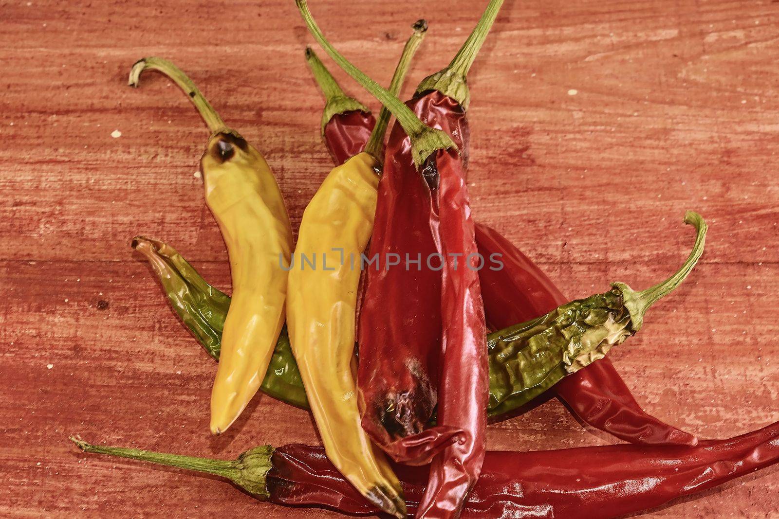 Shrinking and mould chili peppers on red wooden background. Rotten chili peppers.