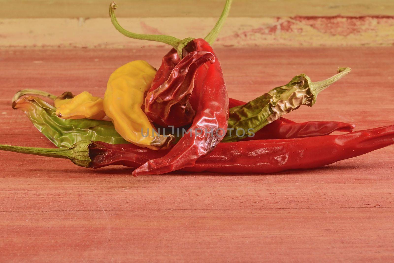 Shrinking and mould chili peppers on red wooden background. Rotten chili peppers by roman_nerud