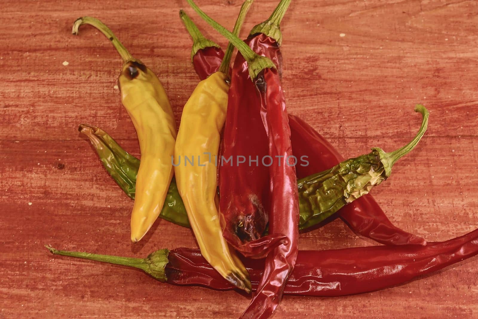 Shrinking and mould chili peppers on red wooden background. Rotten chili peppers by roman_nerud