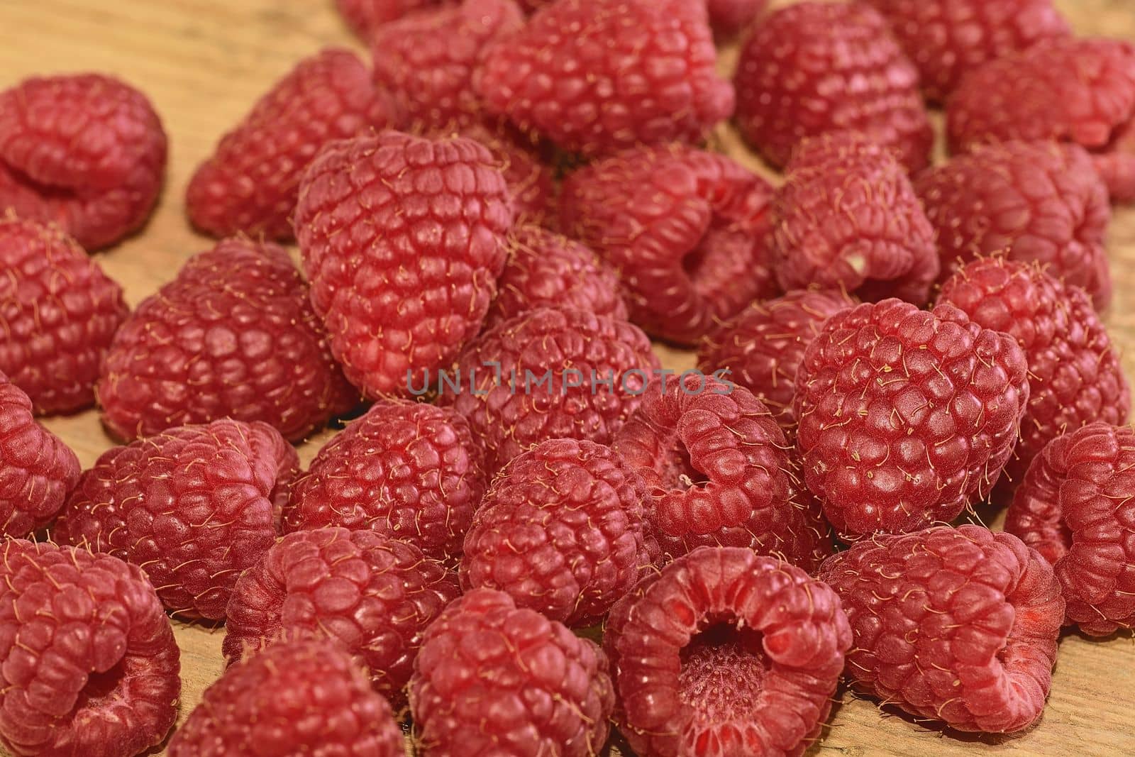 Red-fruited raspberries on wooden background. Raspberries background. Close-up by roman_nerud