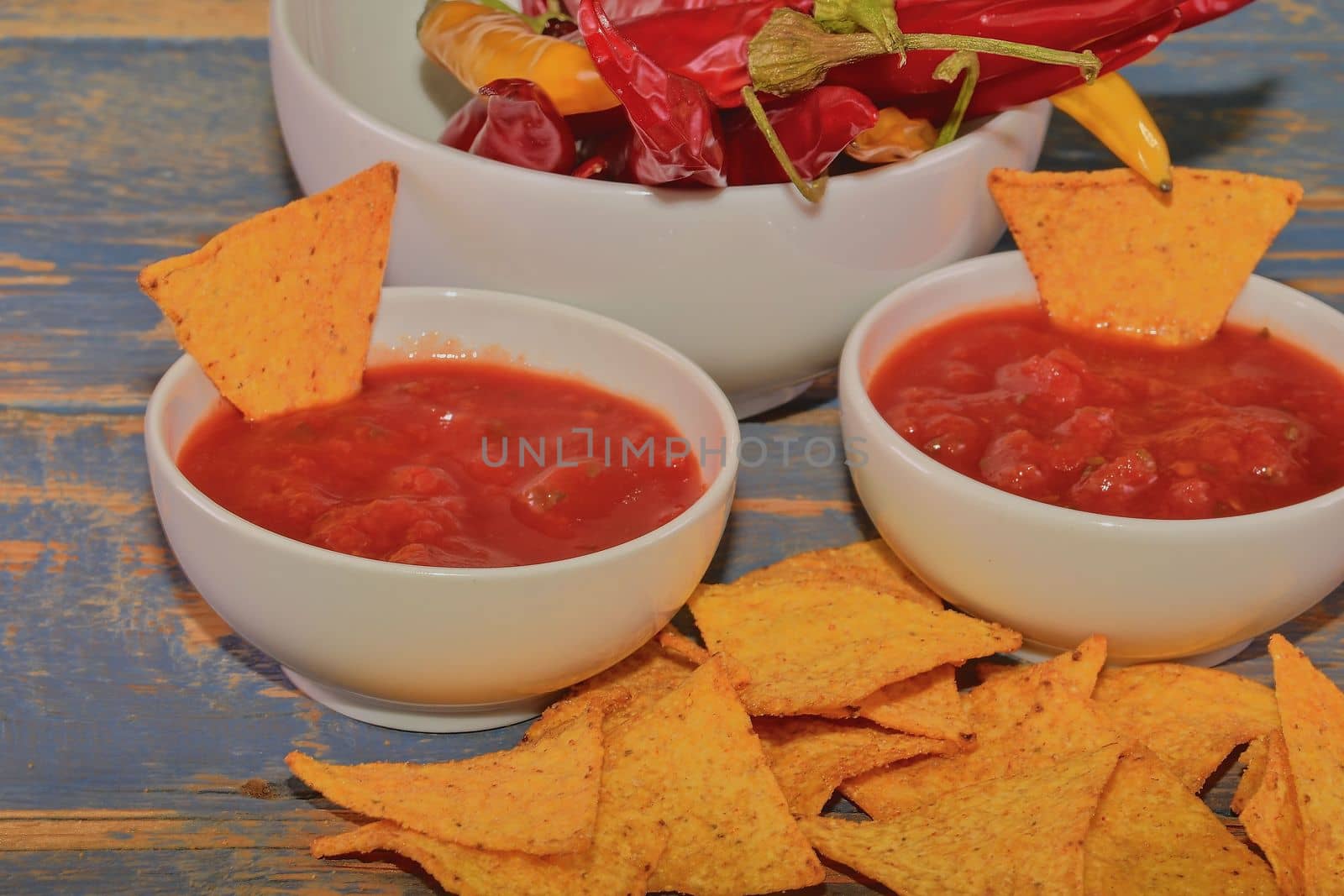 Chili corn-chips with salsa dip and chili peppers on wooden background by roman_nerud