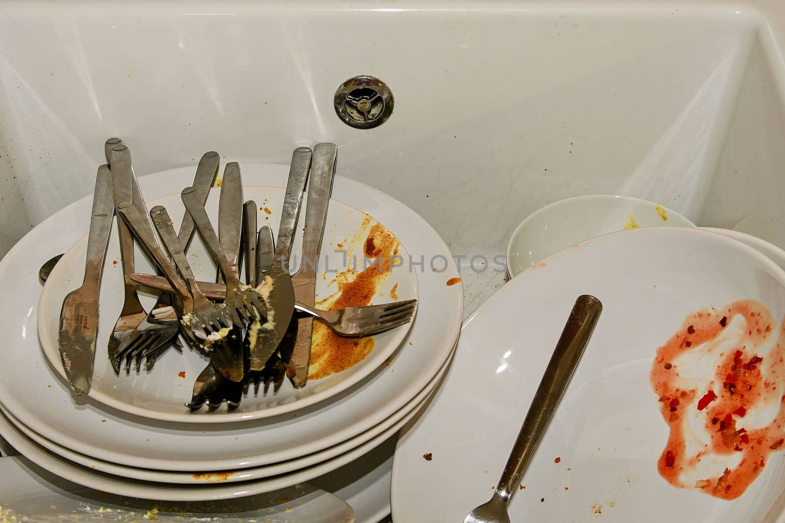 Dirty dishes and cutlery in a kitchen sink.  by roman_nerud