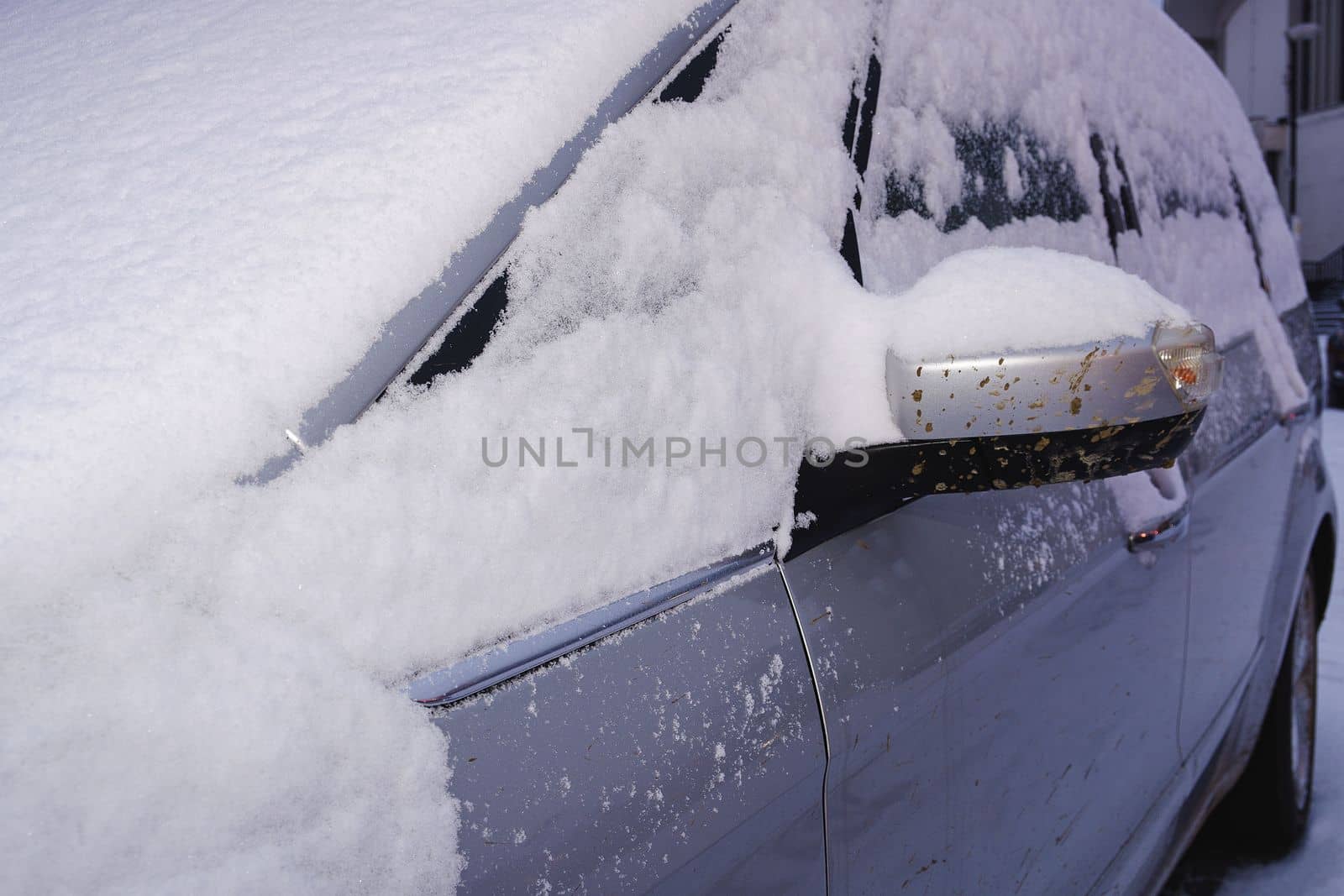 Closeup of a car covered with snow. Silver car in winter