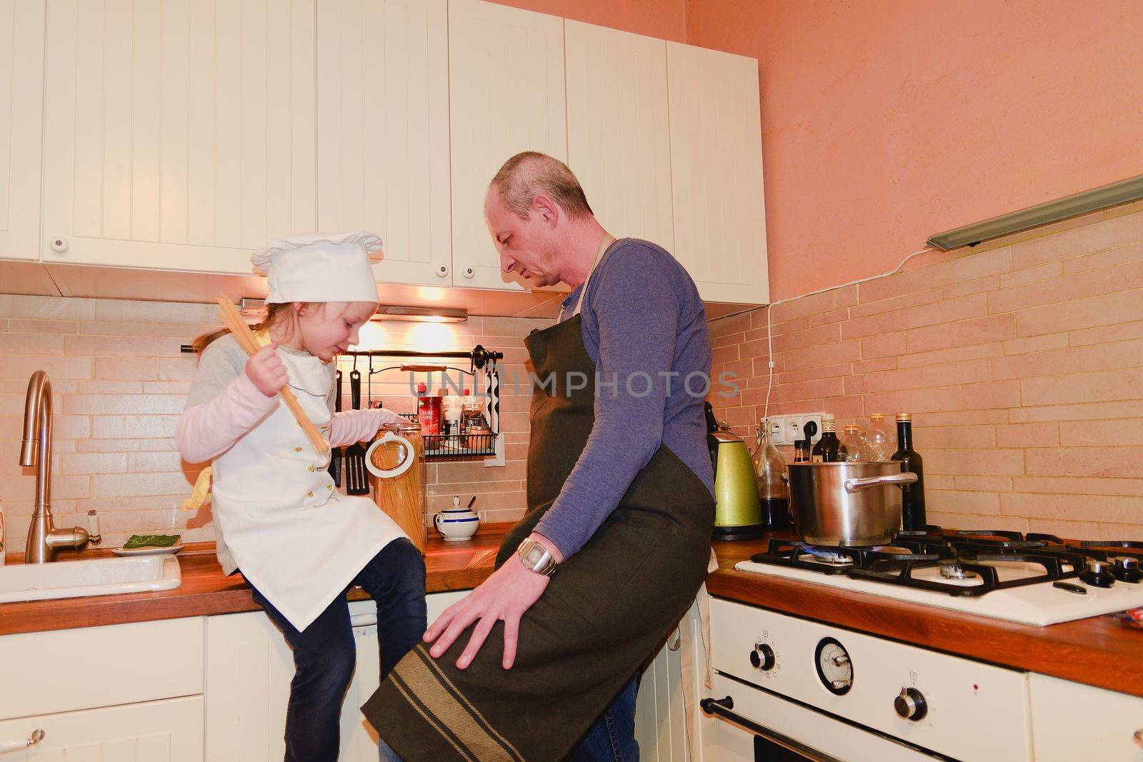 Daughter and father in the kitchen preparing spaghetti to dinner by roman_nerud