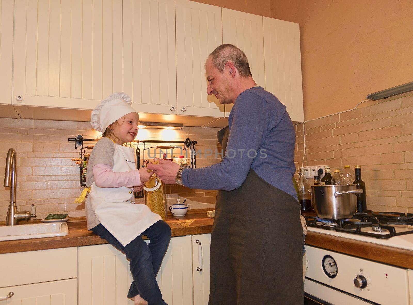Daughter and father in the kitchen preparing spaghetti to dinner by roman_nerud