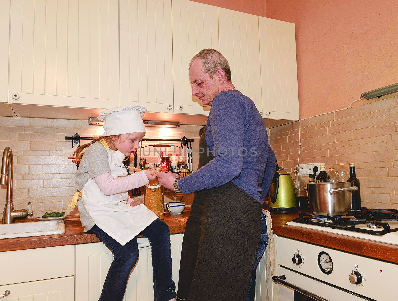 Daughter and father in the kitchen preparing spaghetti to dinner.