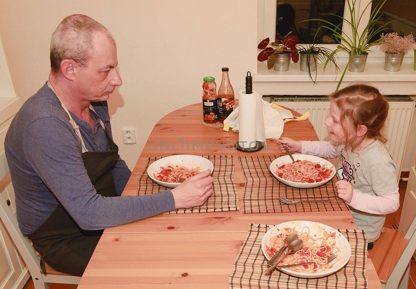 Daughter and father in the kitchen eating spaghetti for dinner.