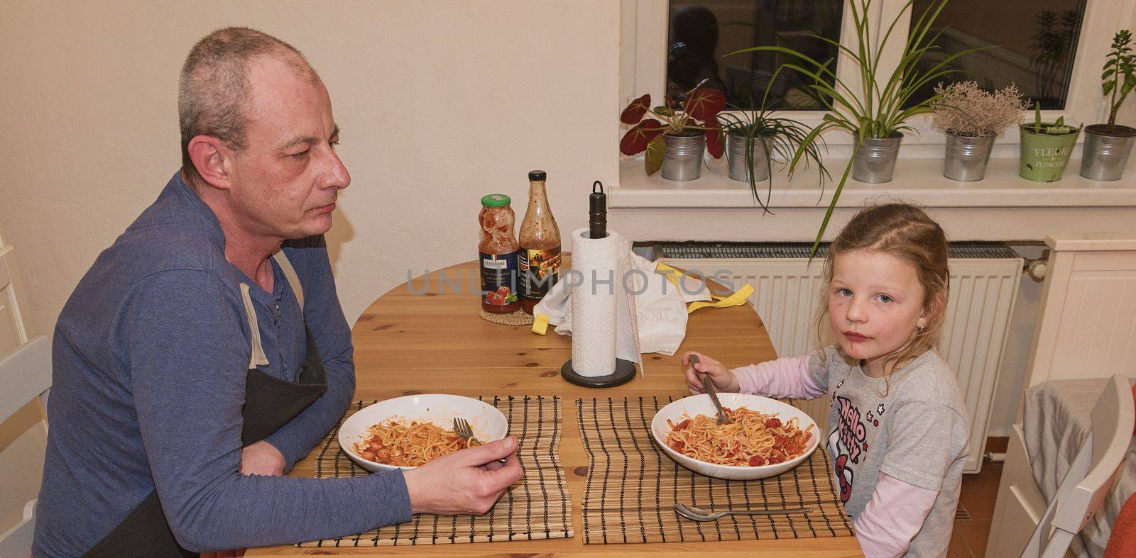 Daughter and father in the kitchen eating spaghetti for dinner.