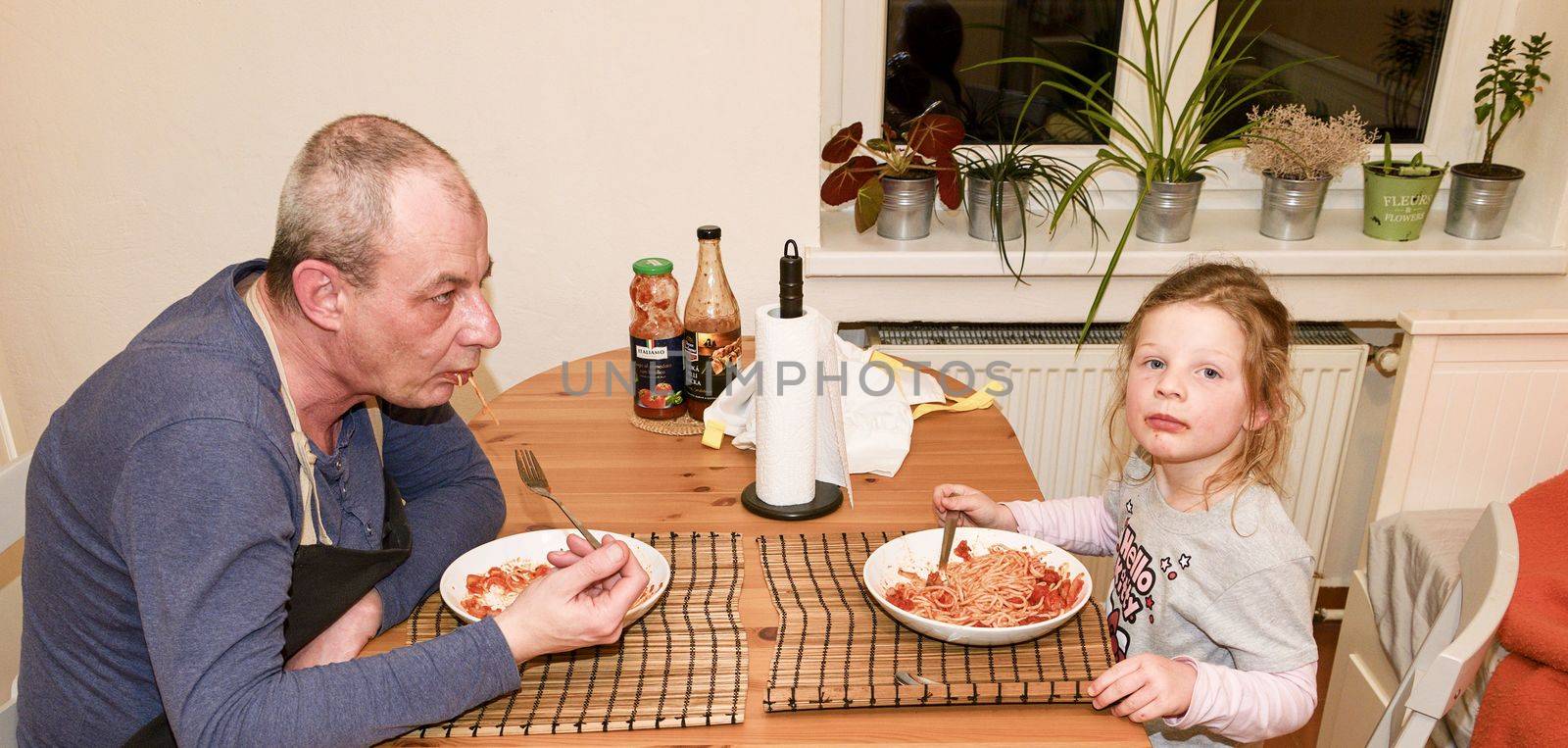 Daughter and father in the kitchen eating spaghetti for dinner by roman_nerud