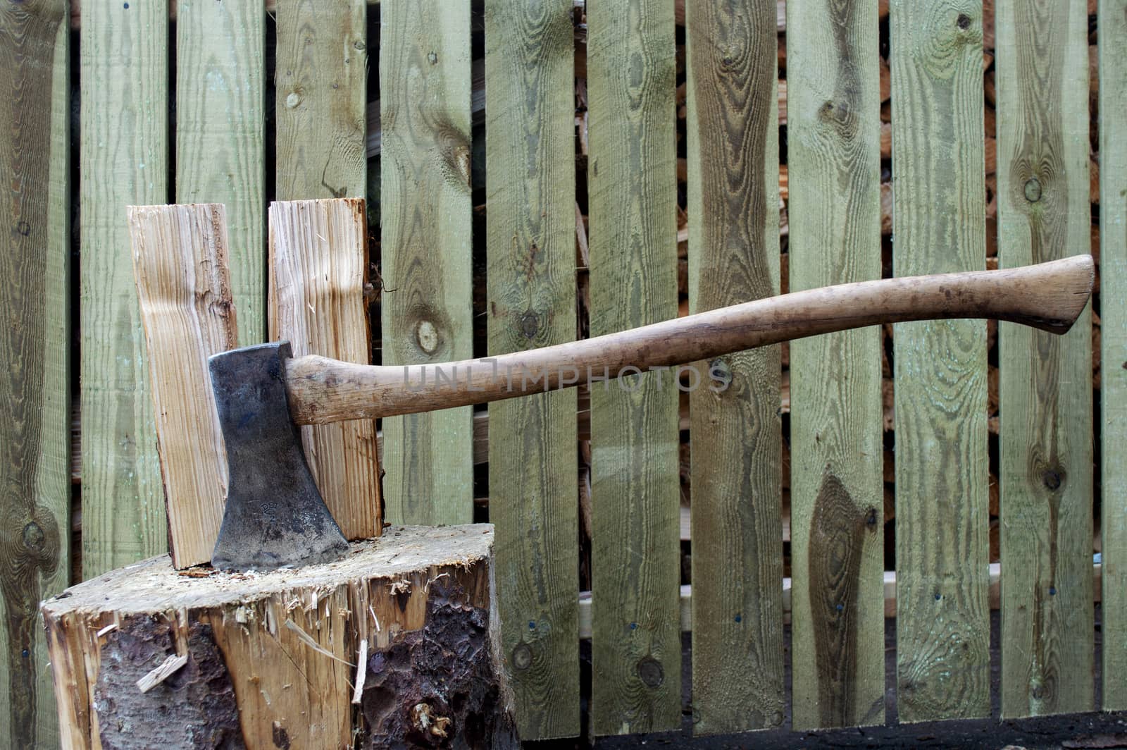 Old vintage axe stuck in wood log used to chop other wood logs.