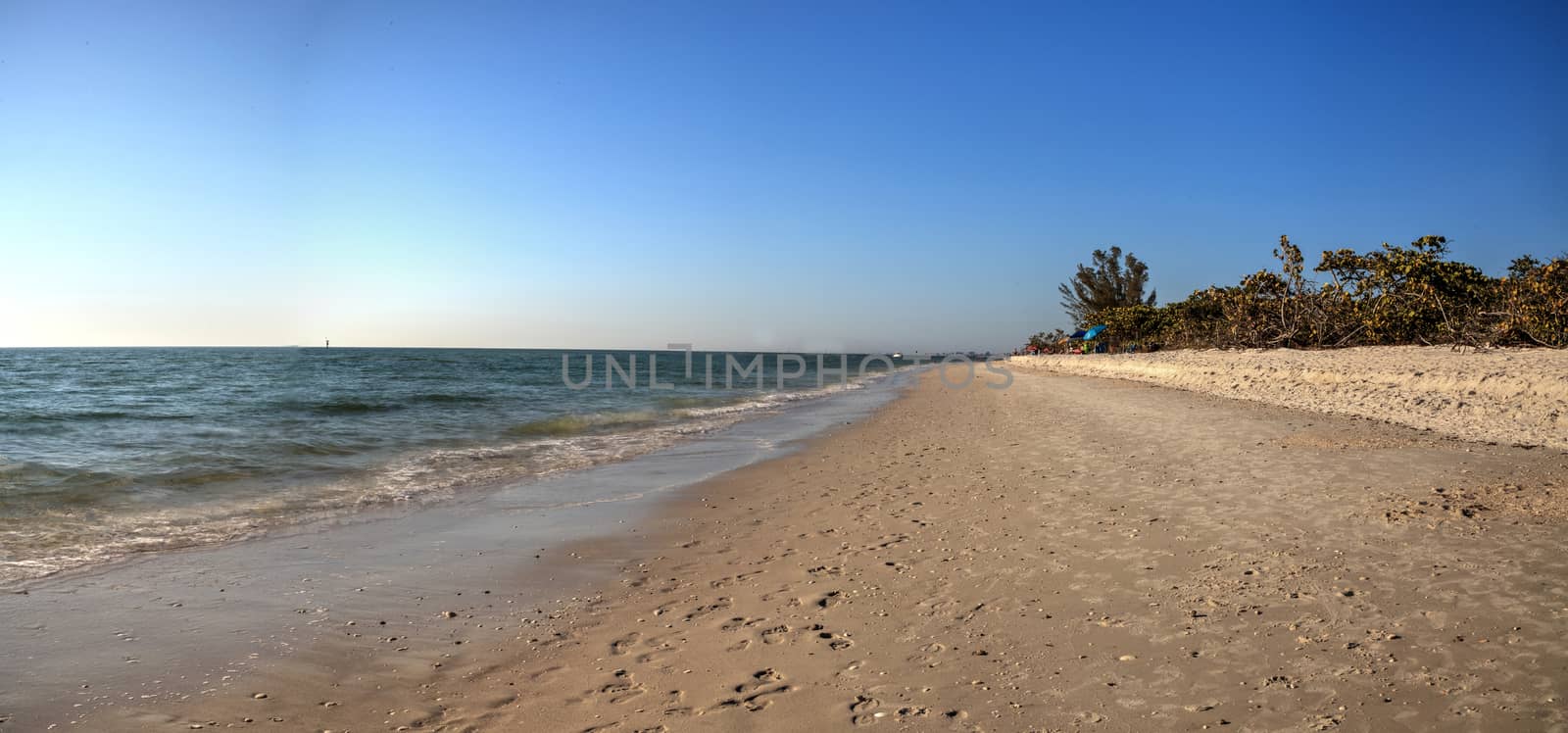 White sand beach of Delnor-Wiggins Pass State Park with a blue sky above in Naples, Florida.