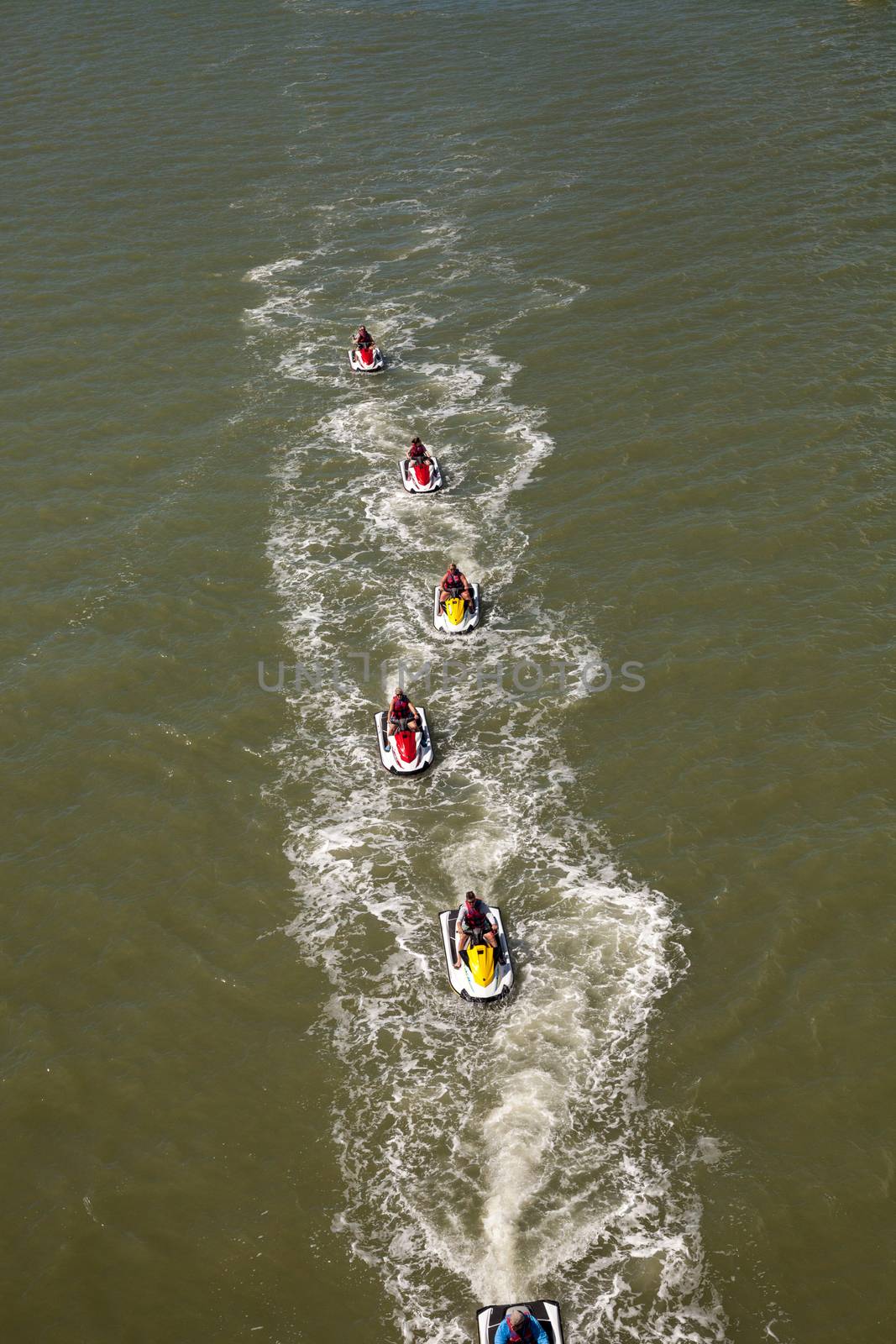 Group of jet skies zip along the ocean in a straight line, making waves in the ocean in the bay in front of Marco Island, Florida