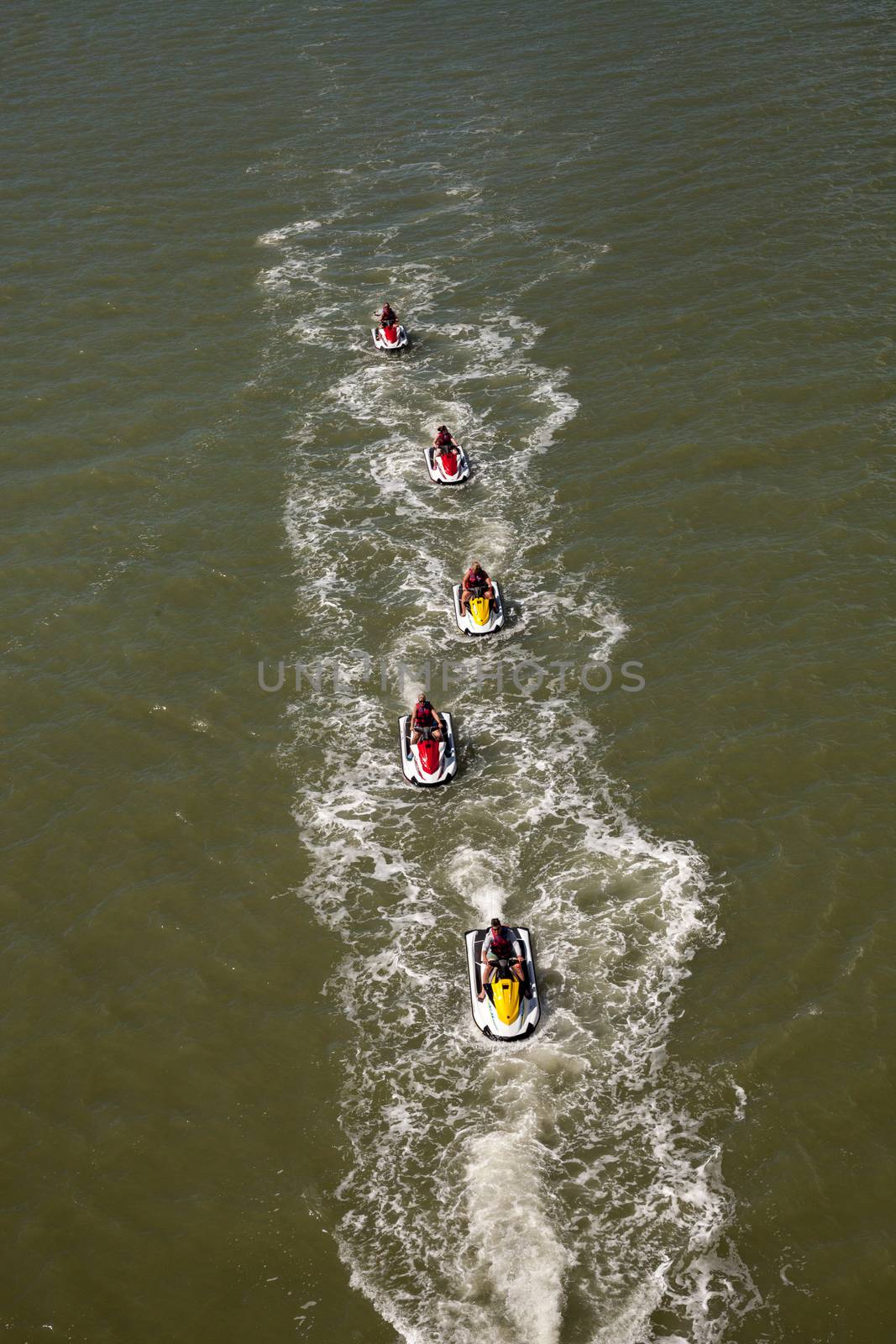 Group of jet skies zip along the ocean in a straight line by steffstarr