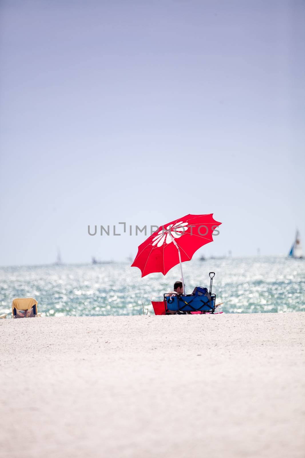 Blue sky over a red umbrella and white sand on Tigertail Beach on Marco Island, Florida