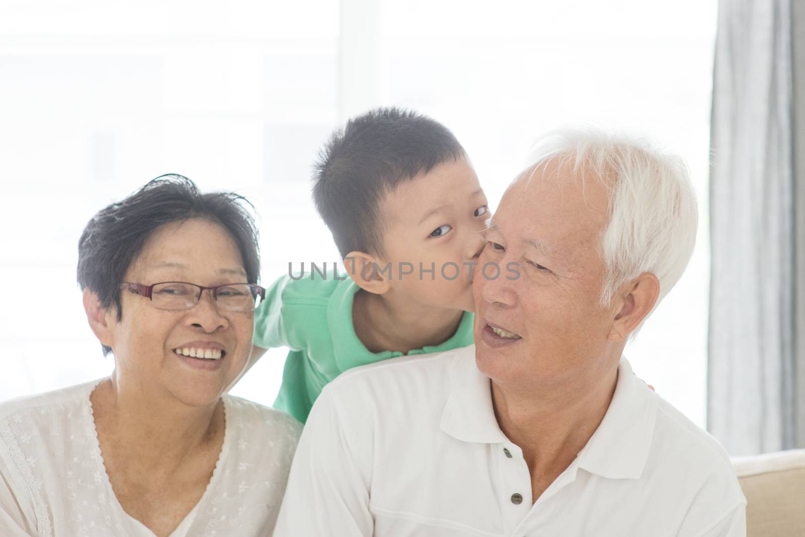 Portrait of happy Asian grandchild kissing grandparents at home, old senior retired people and child indoor lifestyle.