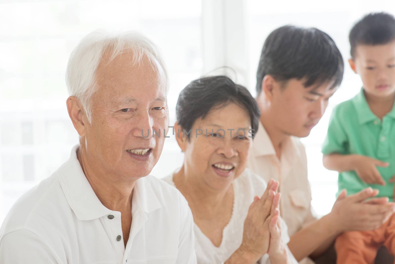 Candid of happy Asian family relaxed at home, clapping hands, multi generations people indoor lifestyle.