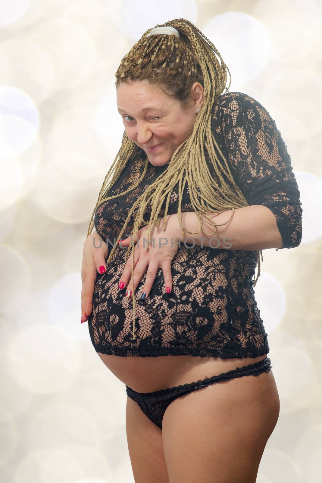 A beautiful pregnant woman holding her abdomen and blinking to camera, isolated with work path.