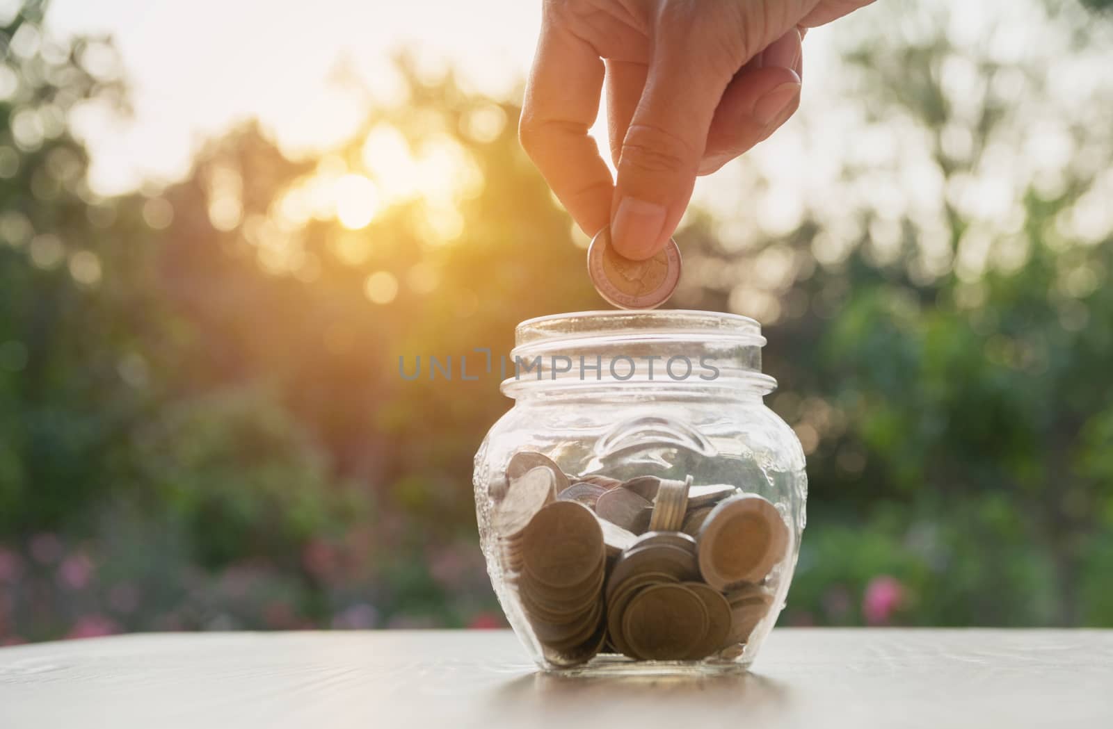 Hand of man holding coin and drop into the glass. Financial stock market in accounting market economy analysis.