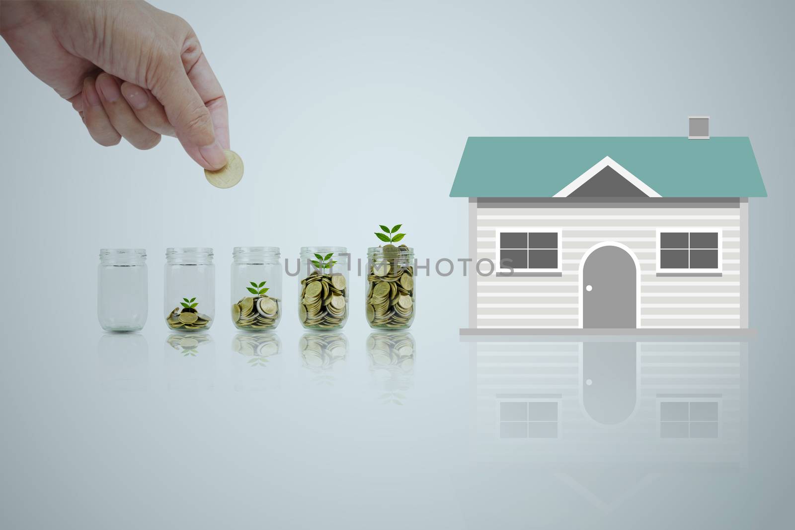 Hand of man holding coin and drop into the glass. Save money for a house concept.