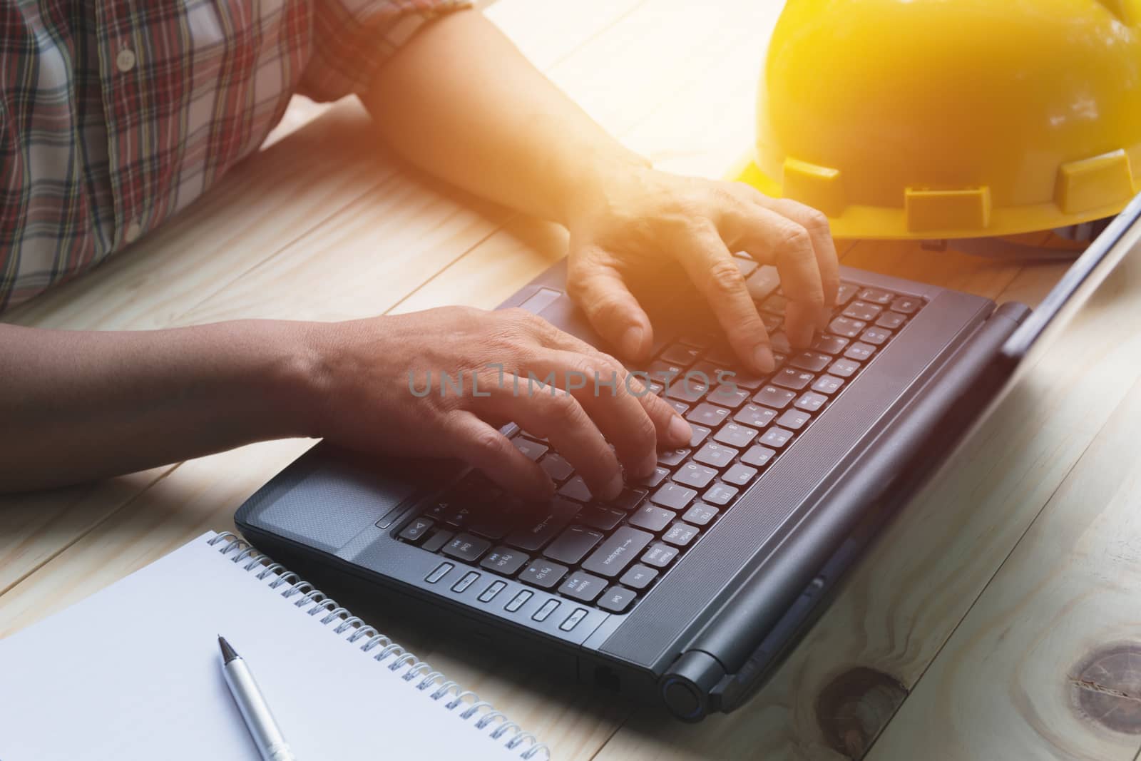 Architect engineer using laptop for working with yellow helmet on table.