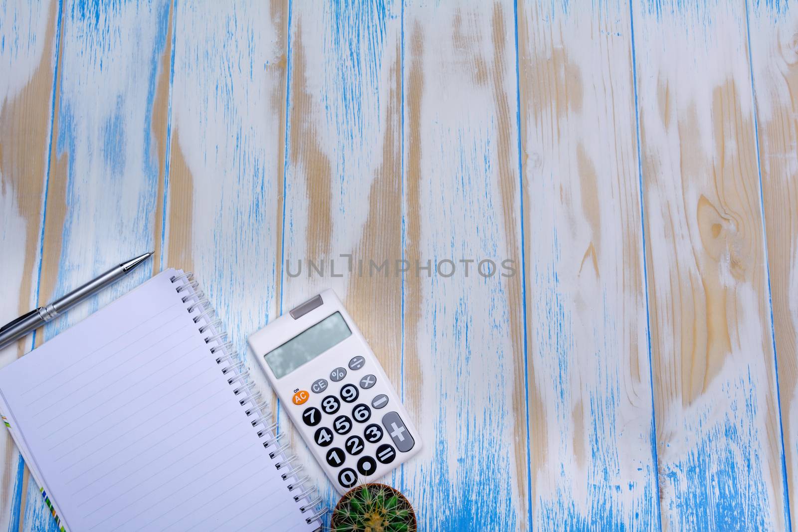 Top view of note book, pen and calculator on wooden table background with copy space.