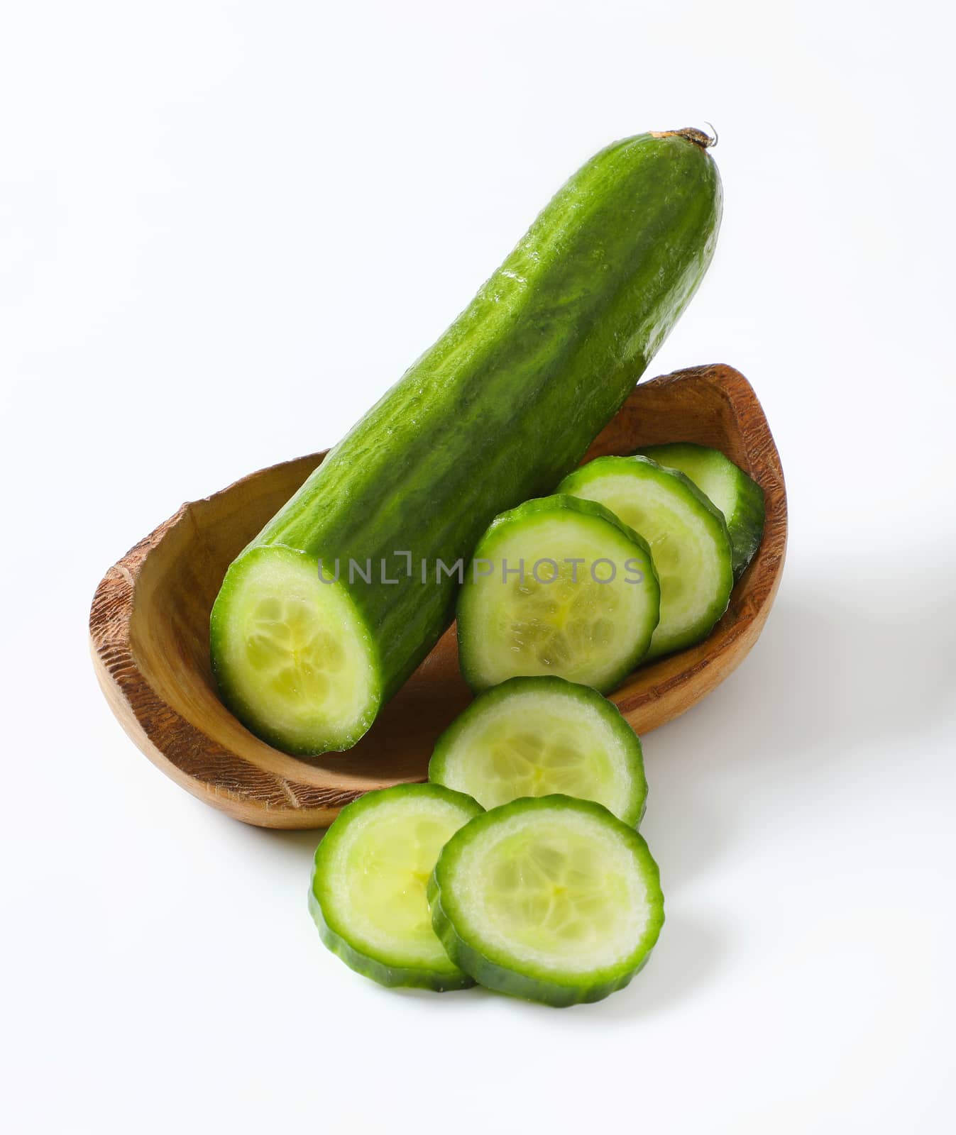 sliced green cucumber in wooden bowl