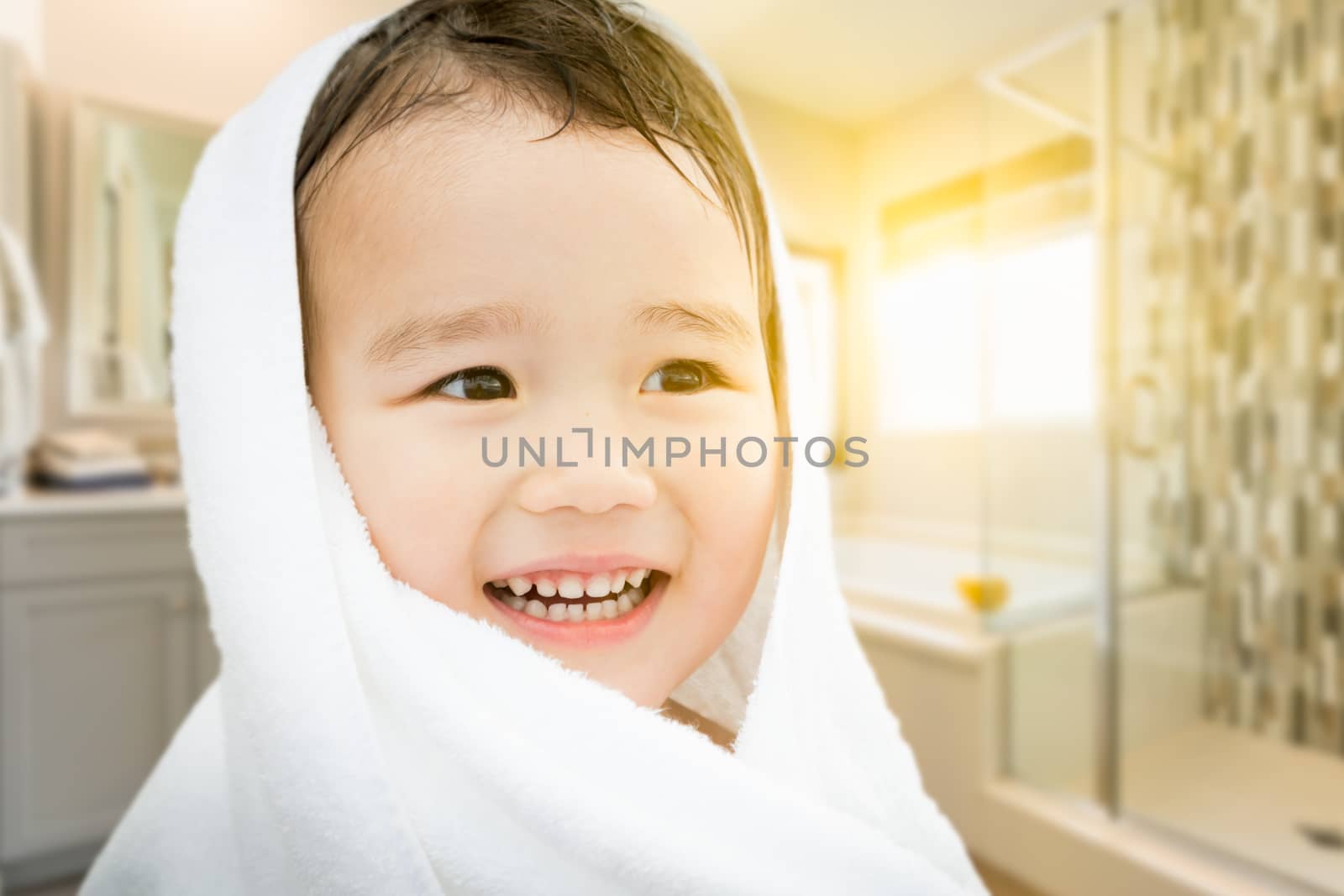Happy Cute Mixed Race Chinese and Caucasian Boy In Bathroom Wrapped In A Towel.
