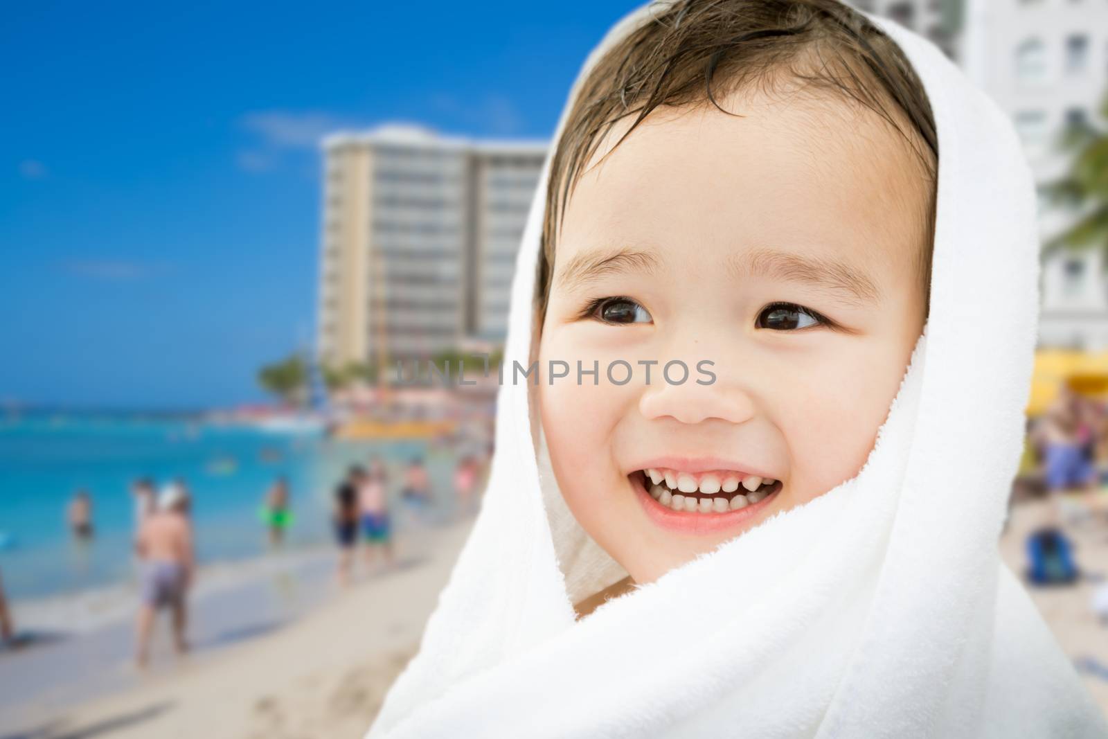 Happy Cute Mixed Race Chinese and Caucasian Boy On Waikiki Beach, Hawaii Wrapped In A Towel.