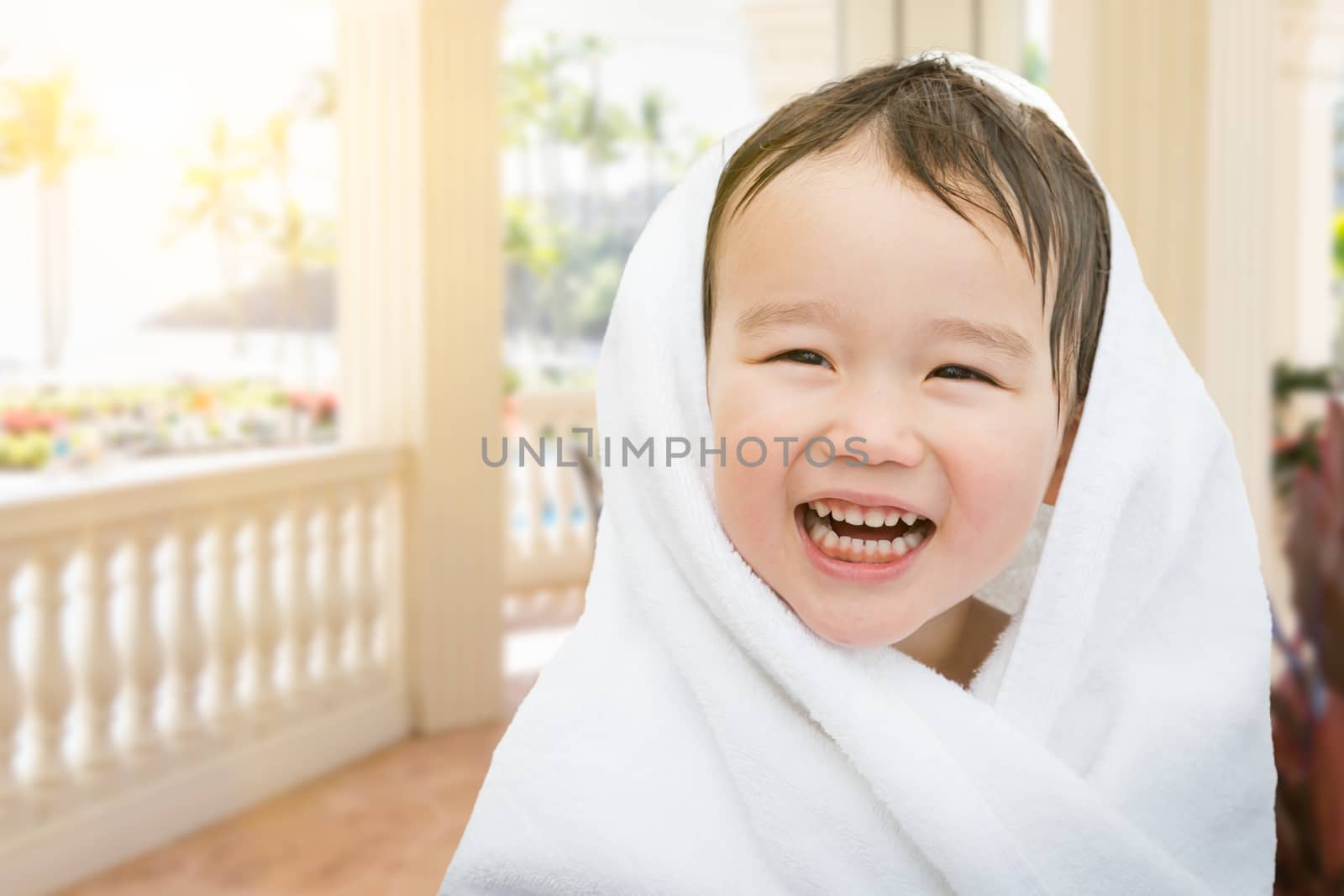 Happy Cute Mixed Race Chinese and Caucasian Boy On Tropical Patio Wrapped In A Towel.