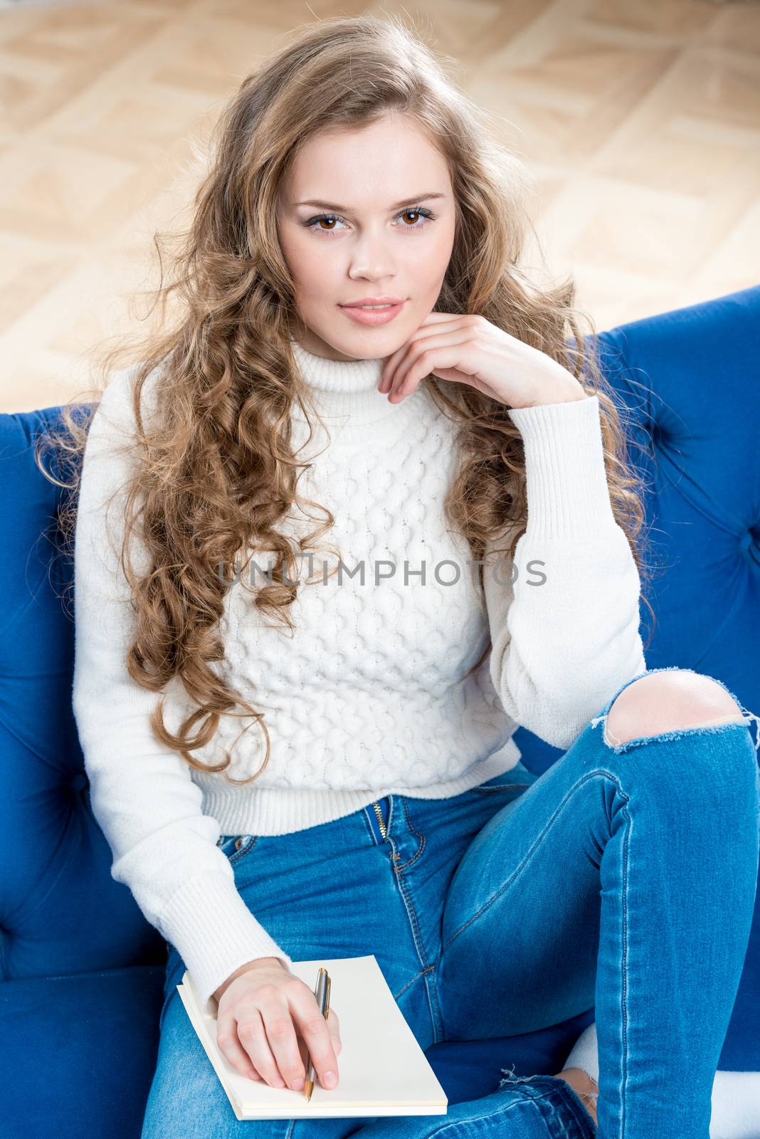 vertical portrait of a pretty girl in a warm sweater on the couch