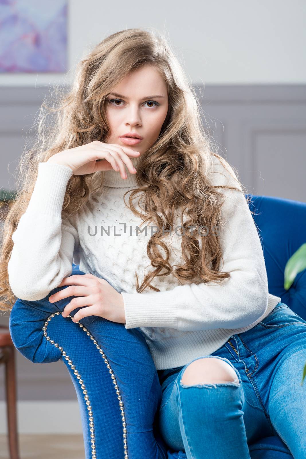 charming girl sitting in living room on blue couch and posing