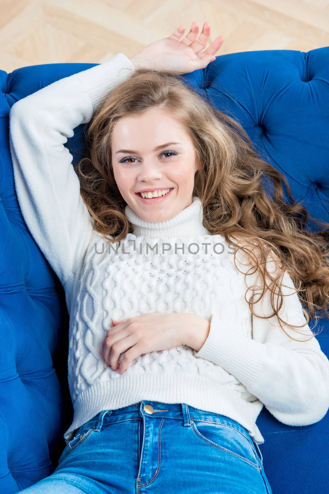 laughing young woman posing on couch in living room in sweater