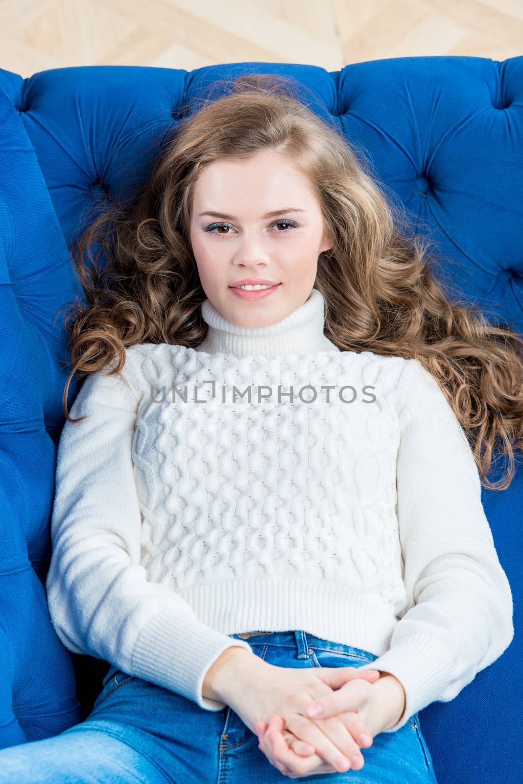 happy woman with long hair lies on sofa in living room