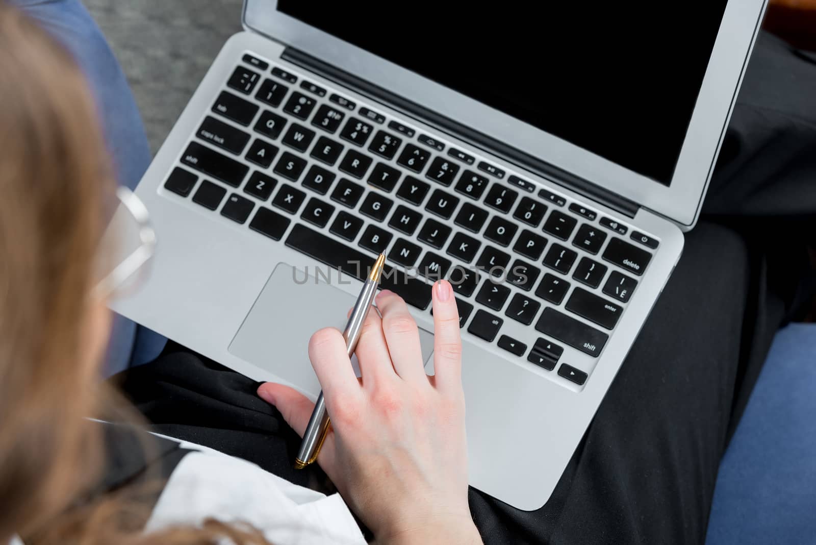 laptop, behind which works businesswoman top view closeup