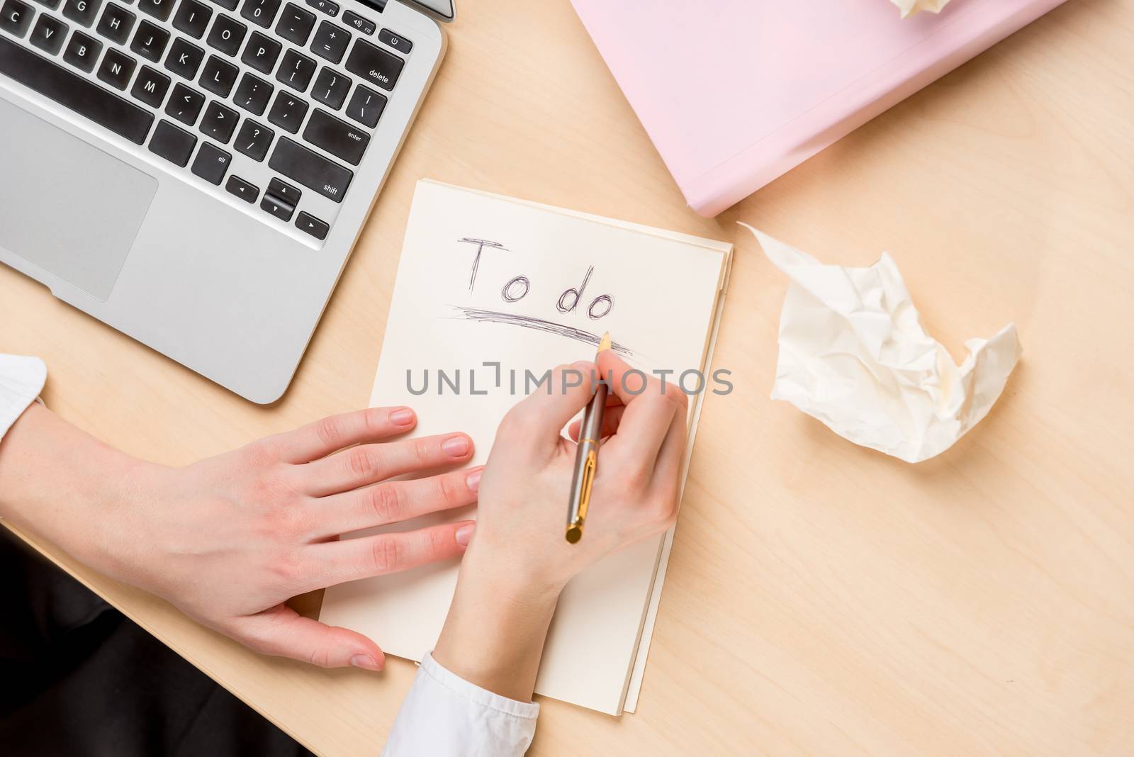 businesswoman making notes in a notebook, top view on the desktop, in the frame of the hand