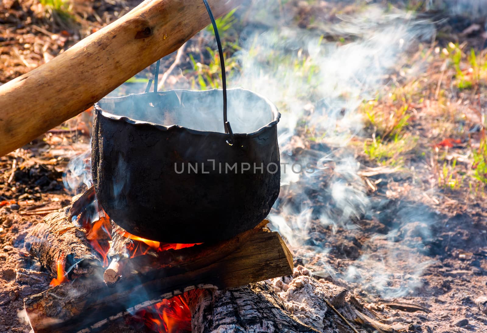 cauldron in steam and smoke on open fire by Pellinni