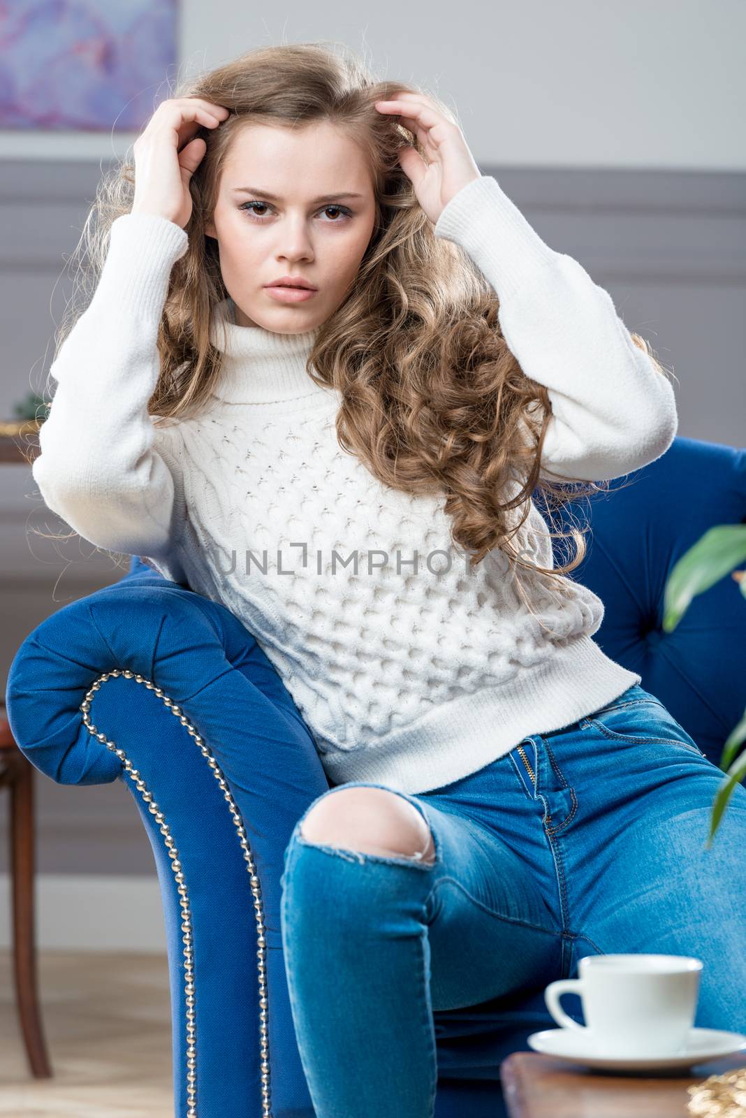 charming young girl sitting in living room on blue couch and pos by kosmsos111