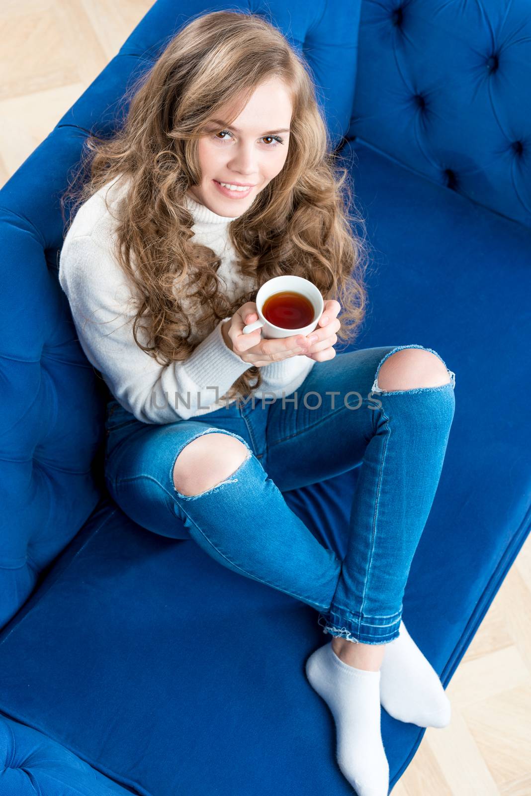 pretty girl in a warm sweater with a cup of tea on the sofa in the living room top view