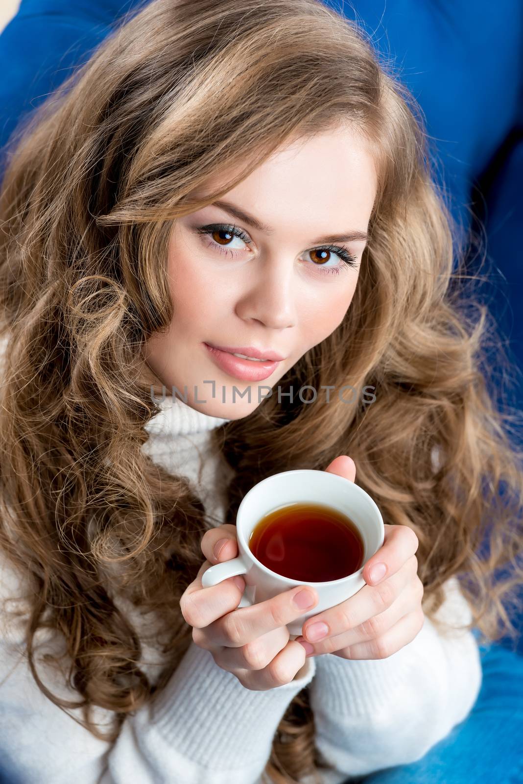 close-up portrait of a beautiful girl with a cup of tea on the couch