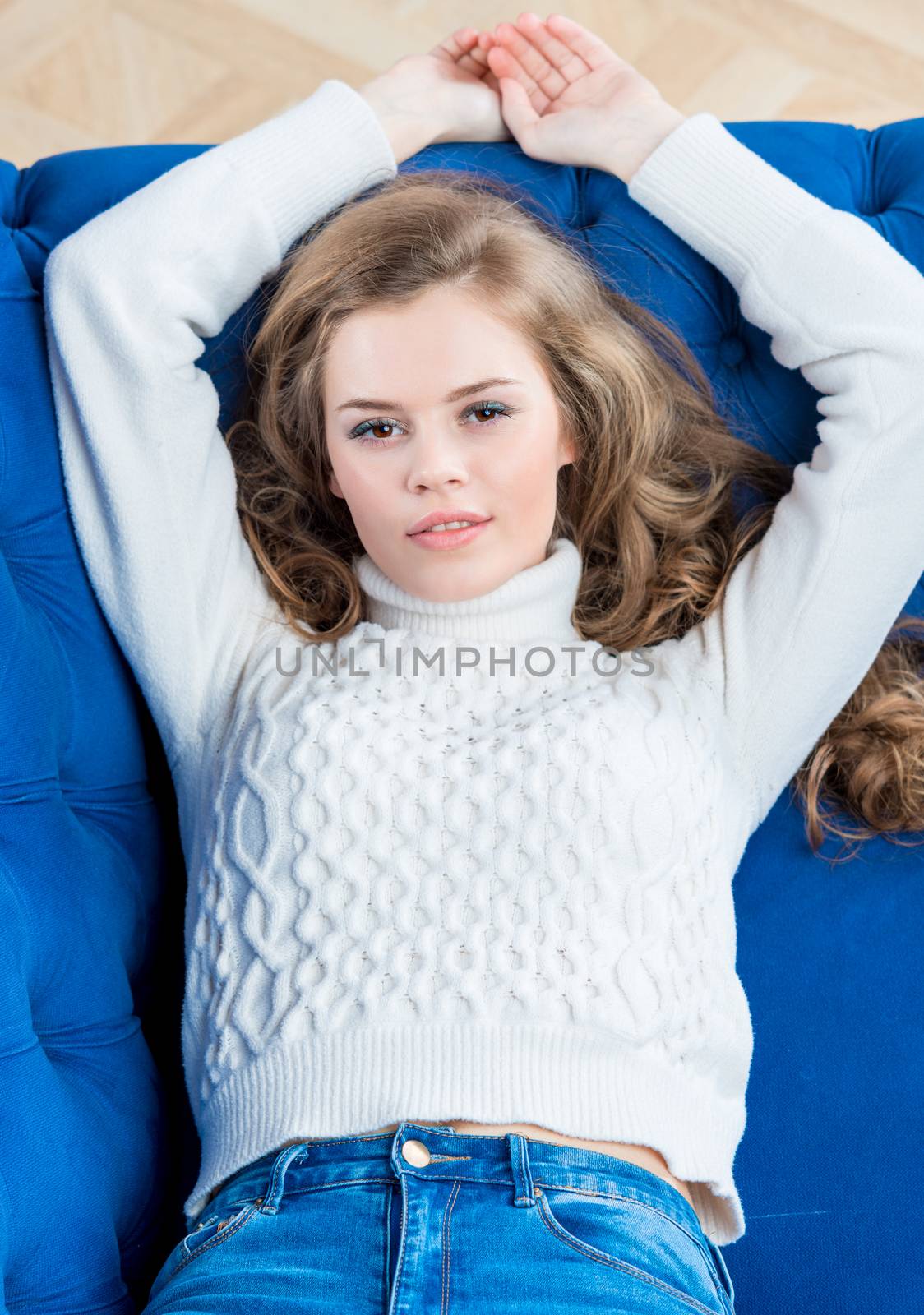 cute young girl posing on couch in living room in sweater