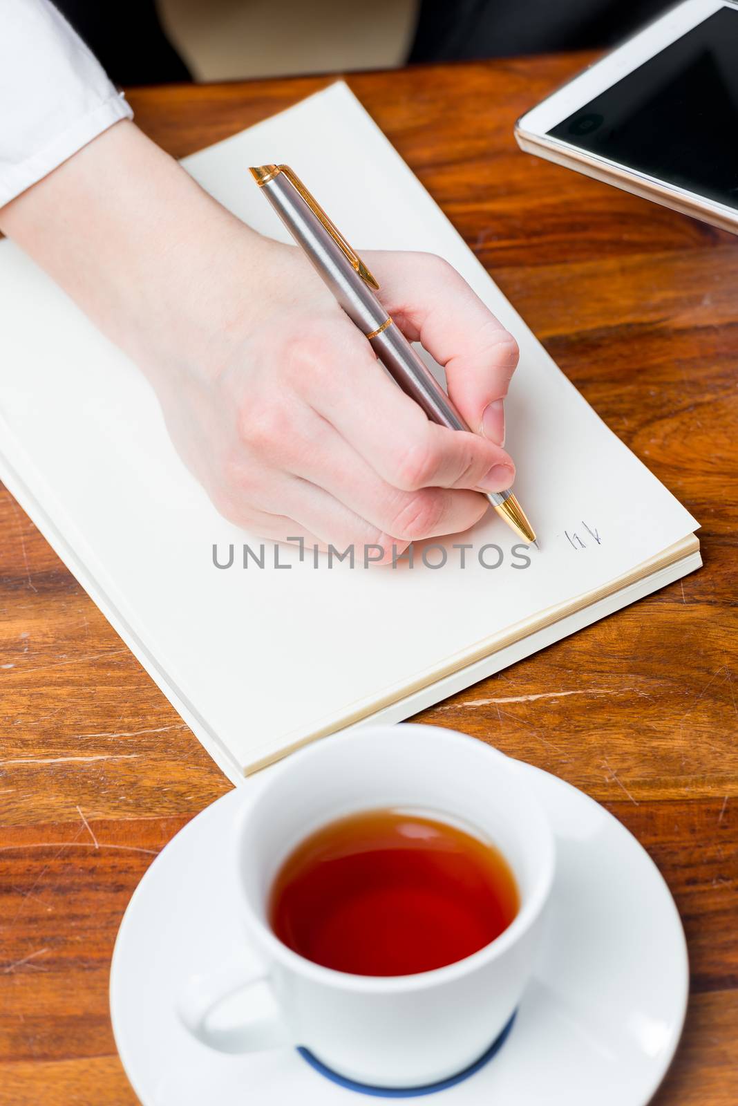 female hand makes a note in a notebook with a pen, top view of a close-up