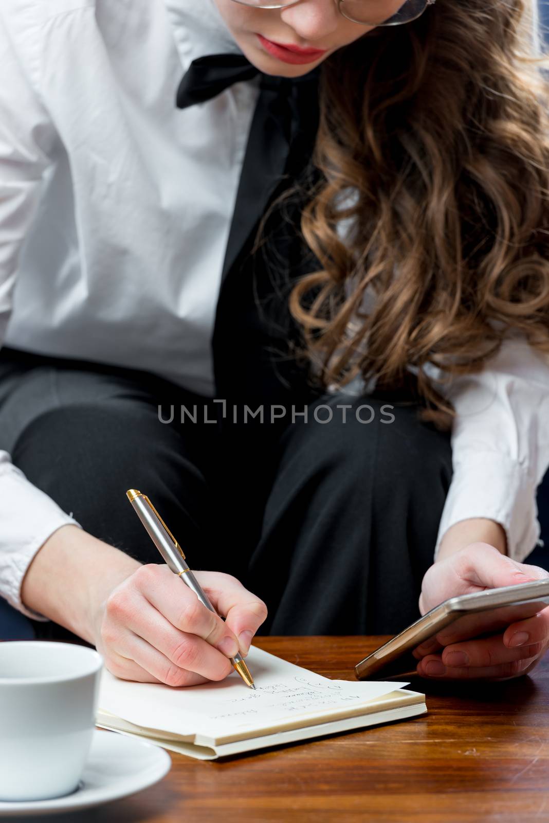 close-up of a businesswoman making a note in a notebook by kosmsos111