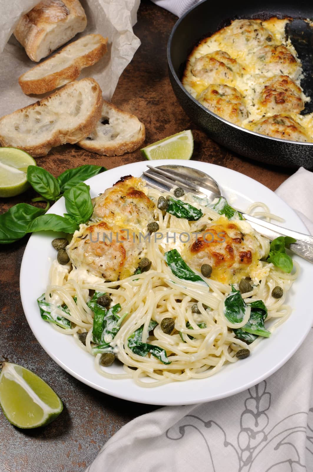 Spaghetti with chicken meatballs in cheese cream sauce , spinach and capers